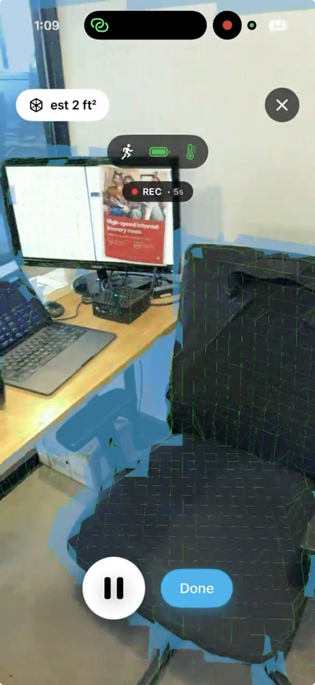 The PRISM capture screen on an iPhone during a scan of an office. Captured surfaces are shaded over the live camera view, with a running area estimate, tracking, battery and thermal indicators, and an elapsed recording time.